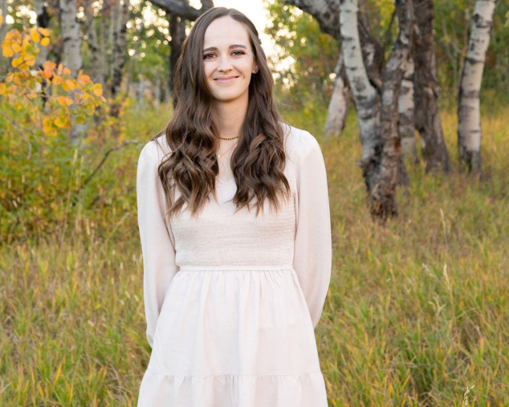 Founder of Cerulean Chemistry Standing in a filed wearing a white dress.
